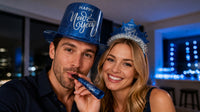 Midnight Blue New Year Party Kit couple: man in a blue foil Happy New Year top hat blowing a blue printed foil horn, woman in a blue Happy New Year tiara with silver fringe